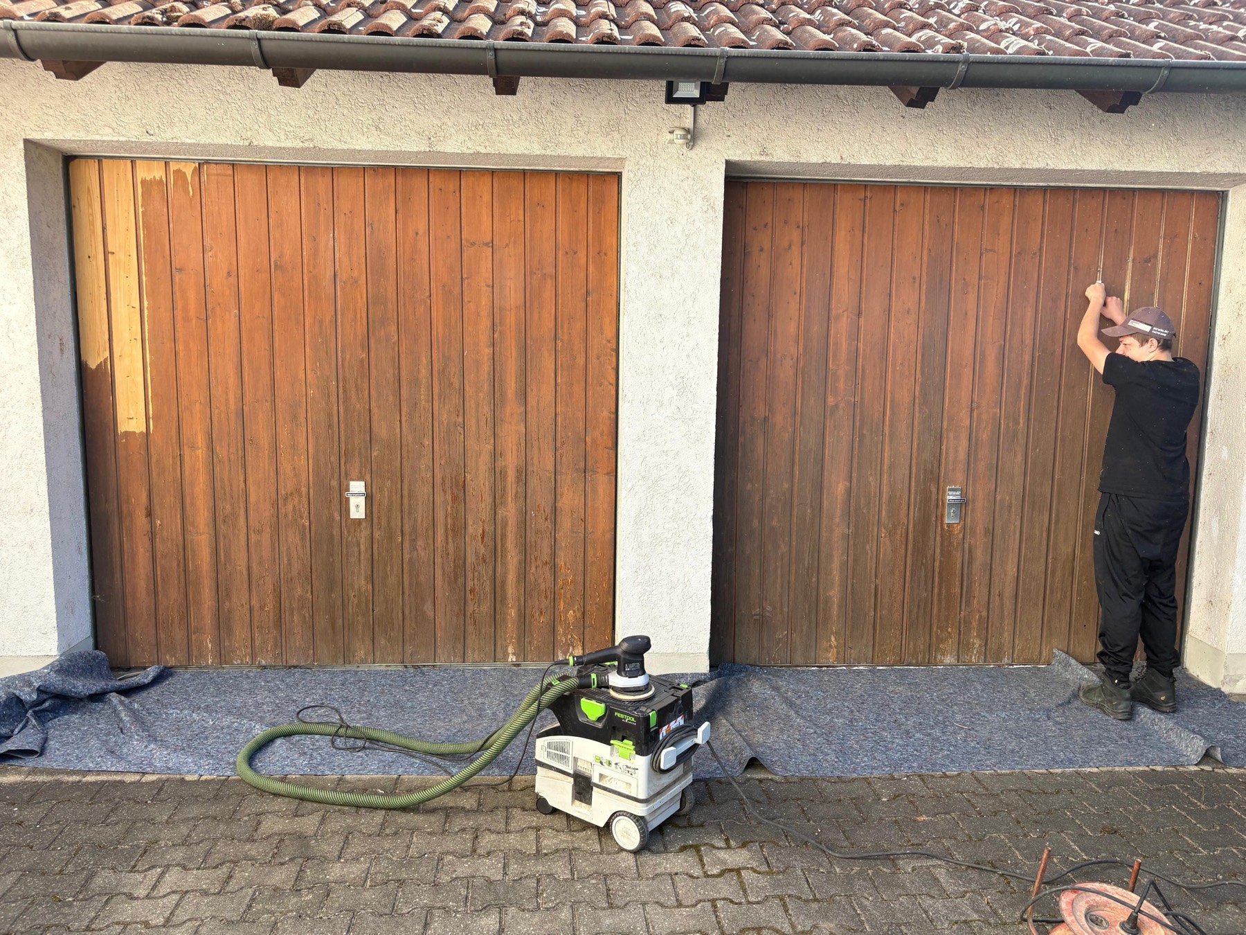 Garagentor-Restauration in Regensburg: alte Lasur wird mit dem Festool-Schleifer abgetragen
